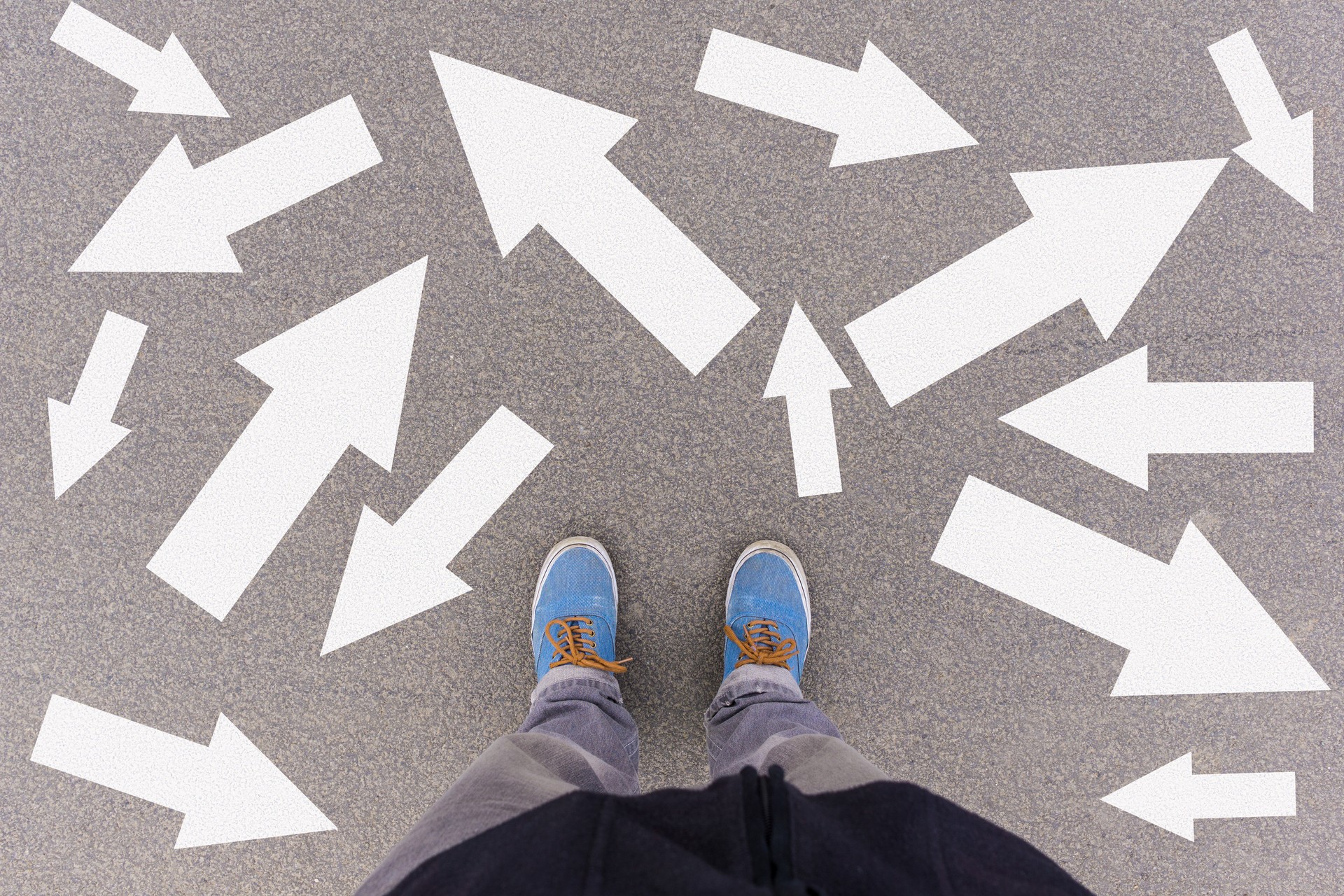 Low Section Of Man Standing Amidst Arrow Symbols On Road